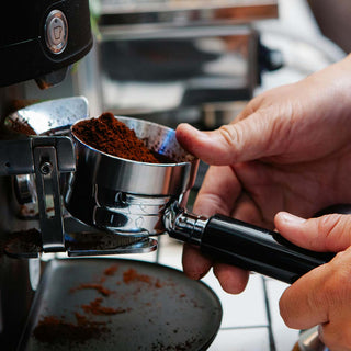 risch gemahlenes Kaffeepulver fällt aus der Kaffeemühle direkt in den Siebträger.