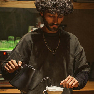 Barista bereitet mit einem Gooseneck-Kessel einen Pour Over Kaffee zu.