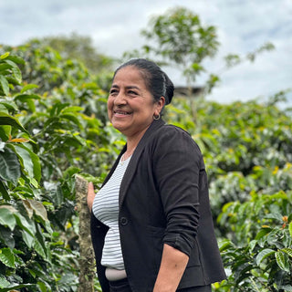 Porträt von Mary Luz Ruiz zwischen Kaffeepflanzen auf ihrer Farm El Placer in Kolumbien.