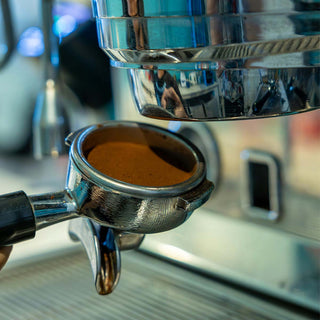 Siebträger mit frisch getamptem Kaffeepulver wird in eine Espressomaschine eingespannt.