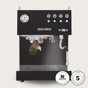 Auf dem Bild ist die schwarze Siebträger-Espressomaschine PID DUO von ASCASO zu sehen. Mit einem Siebträger, der einen Griff aus Holz hat. Rechts unten im Bild befinden sich zwei Zeichen, die darauf hinweisen, dass es sich um einen offiziellen Markenpartner von ASCASO handelt und dass eine Garantieverlängerung von 5 Jahren gewährleistet wird wird.