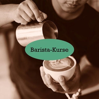 Barista gießt Latte Art in eine Tasse; darüber steht Barista-Kurse auf einem grünen Label.