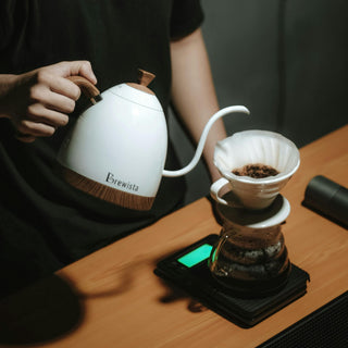 Kaffee wird mit einer weißen Brewista Kanne in einen Handfilter auf einer digitalen Waage aufgegossen.
