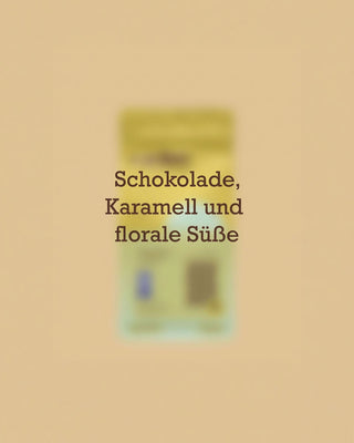 Geschmacksprofil des entkoffeinierten AMORI Chevere Kaffees aus Kolumbien mit den Aromanoten Schokolade, Karamell und florale Süße vor einer unscharfen Kaffeeverpackung.