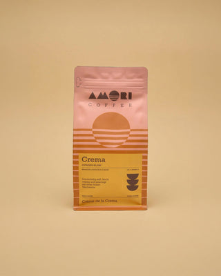 AMORI Coffee Crema Espresso-Blend aus 100 % Arabica in rosa-orangefarbener Kaffeeverpackung mit gelbem Etikett und den Herkunftsländern Brasilien, Costa Rica und Indien.