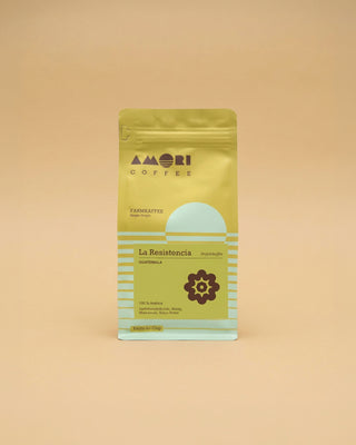 AMORI Coffee La Resistencia Farmkaffee aus Guatemala, 100 % Arabica, in gelb-grüner Kaffeeverpackung mit hellblauen Streifen, Projekthilfe-Hinweis und Farm-to-Cup-Schriftzug.
