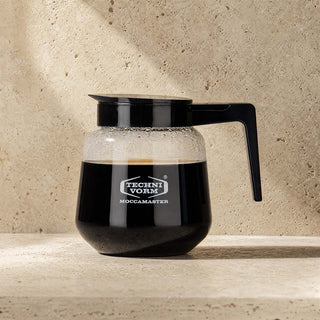 Moccamaster Glaskanne CD Grand/Moccaserver 1,8 L gefüllt mit Kaffee, auf Steinuntergrund vor Travertin-Wand