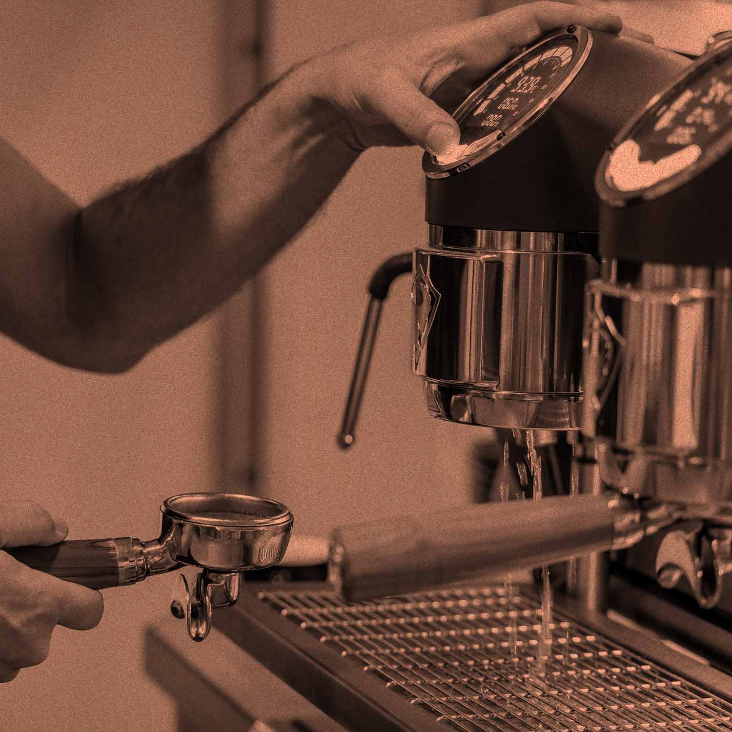 Person hält Siebträger in der Hand und bedient einen Knopf unterhalb der Anzeige einer modernen Espresso-Siebträgermaschine. 