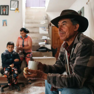 Kaffeebauer der La Resistencia Gemeinschaft in Guatemala sitzt mit seiner Familie im Wohnhaus und trinkt Kaffee aus eigener Ernte.