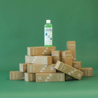 Moccamaster Cleandrip Reinigungsmittel, Flasche mit 250 ml auf gestapelten Verpackungskartons vor grünem Hintergrund