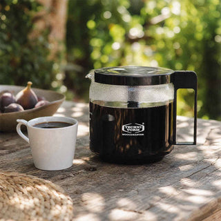 Moccamaster Glaskanne KBG 1,25 L auf Holztisch im Freien, daneben Tasse Kaffee und Schale mit Feigen