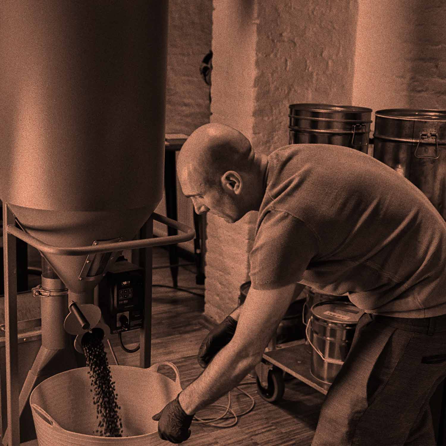 Das Bild zeigt Roberto Cascone, den Inhaber von AMORI Coffee, beim Entsteinen von Kaffeebohnen. Die Kammer ist geöffnet und die Kaffeebohnen fallen in einen Korb.