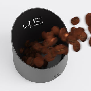 Subminimal Subscale Dosing Cup von oben, mit einfliegenden Kaffeebohnen und sichtbarer LED-Anzeige im Inneren.
